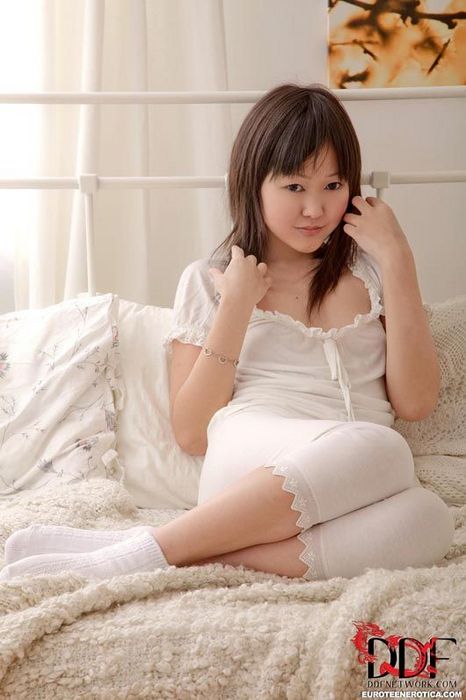 Сексуальная, юная азиатка Aliona L играет на кровати, раздеваясь, снимая белую пижаму и носки